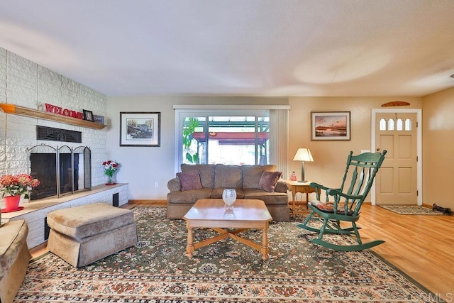 living room with a brick fireplace and wood-type flooring