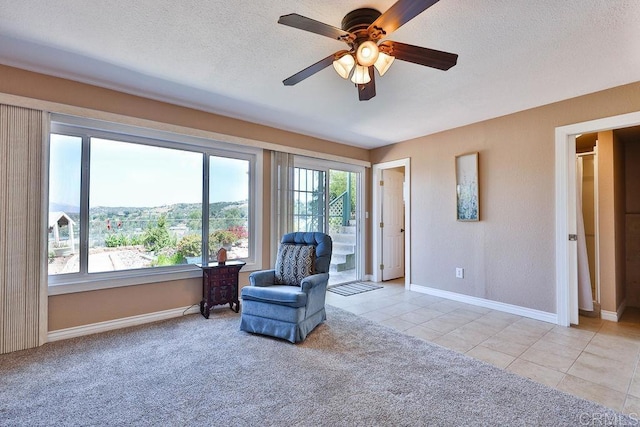 living area featuring a textured ceiling, light tile patterned floors, a wealth of natural light, and ceiling fan