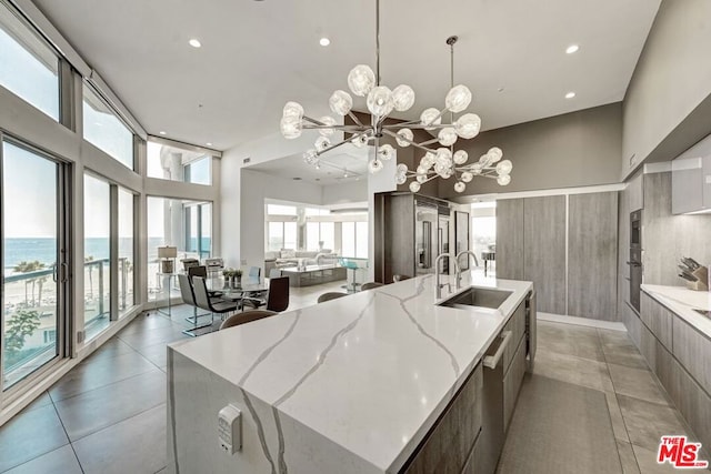 kitchen with sink, a chandelier, a large island, and a water view