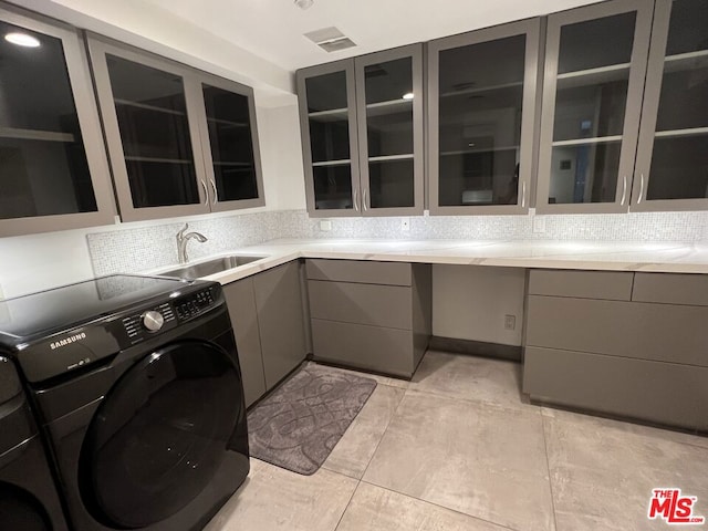 laundry area featuring light tile patterned floors, independent washer and dryer, sink, and cabinets