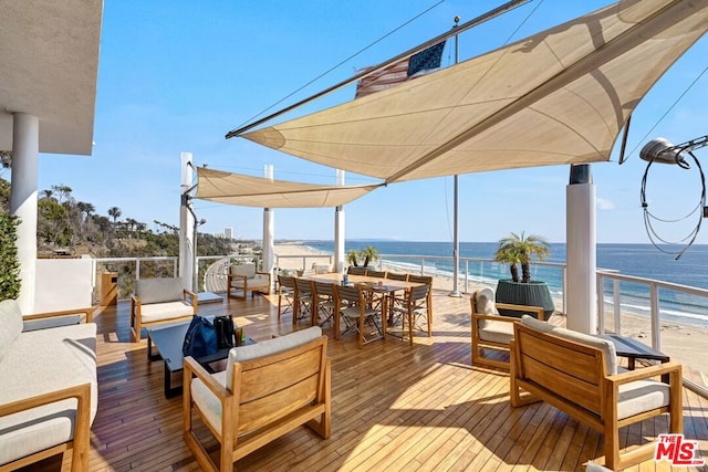 wooden terrace with a view of the beach, a water view, and outdoor lounge area