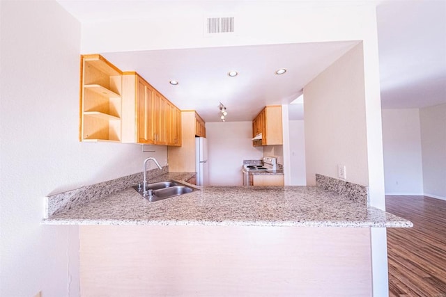 kitchen with kitchen peninsula, light brown cabinetry, white appliances, and sink