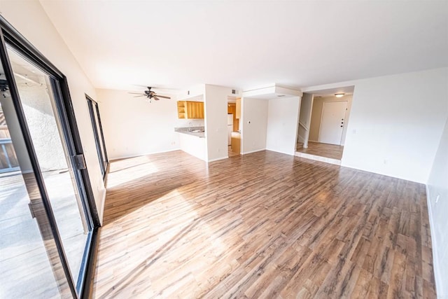 unfurnished living room featuring ceiling fan and light wood-type flooring