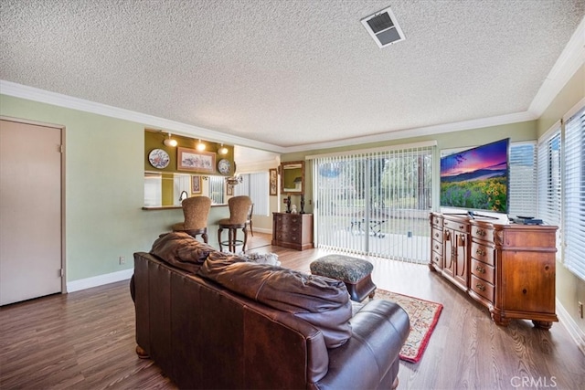 living room featuring visible vents, a textured ceiling, crown molding, and wood finished floors