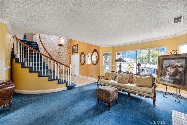carpeted living area featuring visible vents, baseboards, a textured ceiling, and stairs