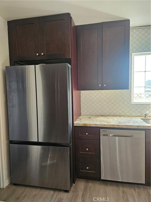 kitchen with light wood-type flooring, stainless steel appliances, and tasteful backsplash