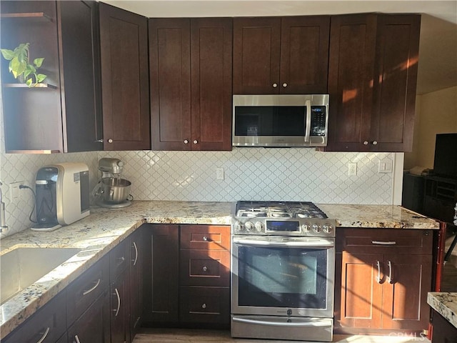 kitchen featuring light stone countertops, sink, stainless steel appliances, and tasteful backsplash