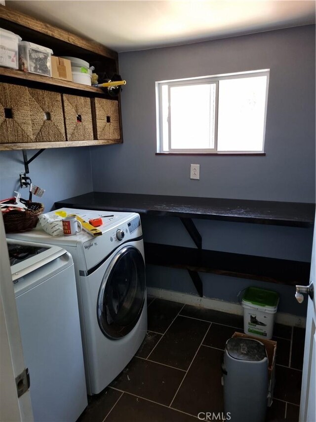 laundry room with washer and dryer and dark tile patterned floors