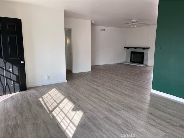 unfurnished living room featuring ceiling fan, hardwood / wood-style floors, and a fireplace