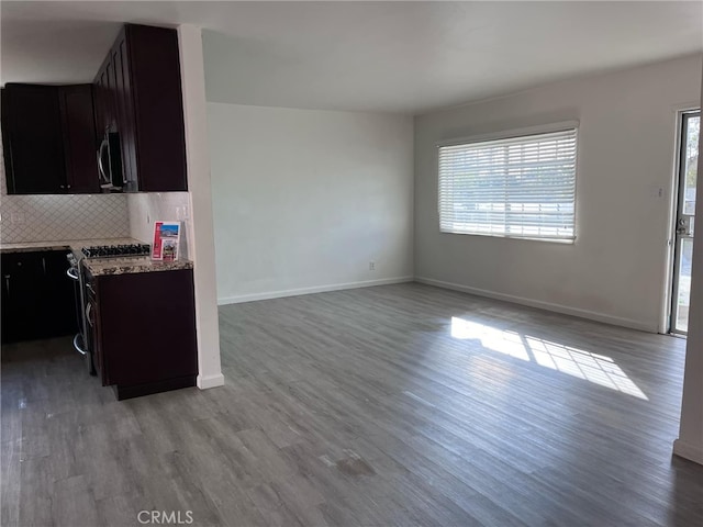 kitchen featuring dark brown cabinetry, appliances with stainless steel finishes, decorative backsplash, and light hardwood / wood-style flooring