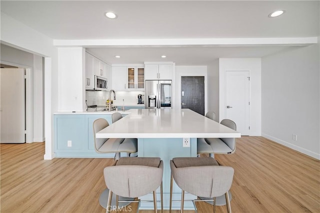 kitchen featuring a breakfast bar area, stainless steel appliances, light hardwood / wood-style flooring, and white cabinetry