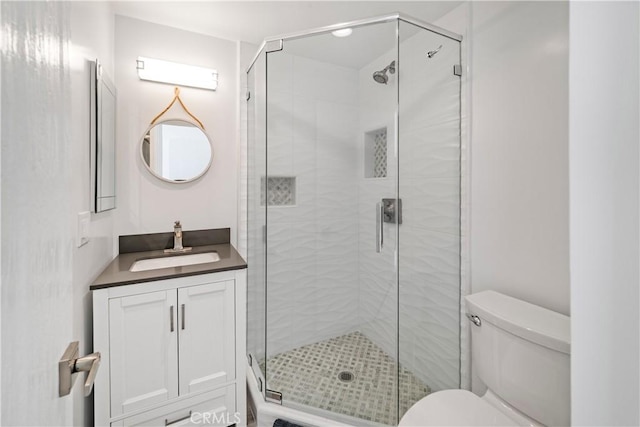 bathroom featuring toilet, vanity, and an enclosed shower