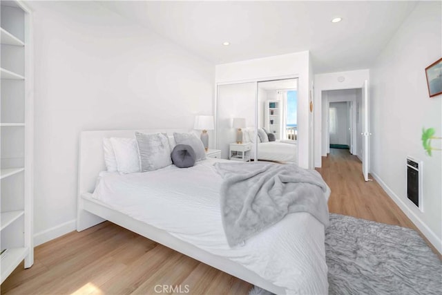 bedroom with heating unit, a closet, and light hardwood / wood-style flooring