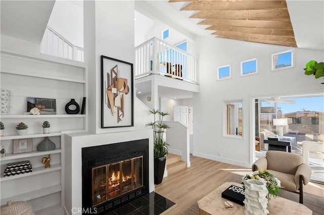 living room with high vaulted ceiling, built in shelves, and hardwood / wood-style flooring