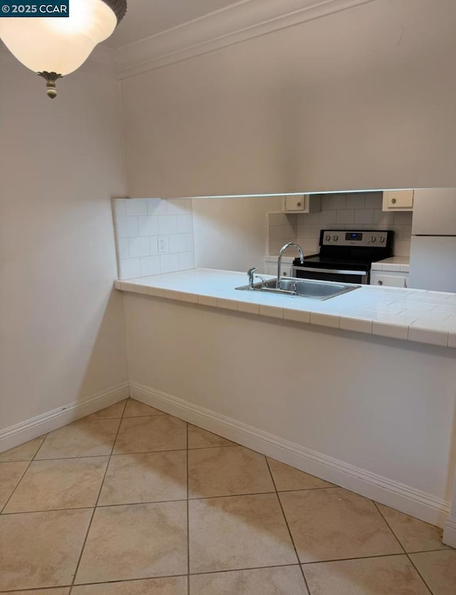 kitchen featuring electric range oven, decorative backsplash, sink, light tile patterned floors, and crown molding