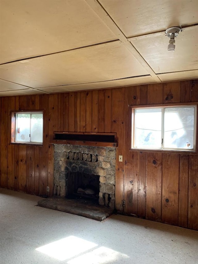 unfurnished living room with wood walls and a stone fireplace