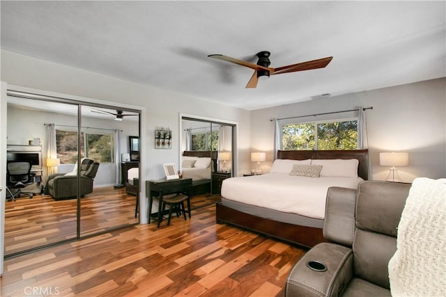 bedroom with ceiling fan, two closets, and wood-type flooring