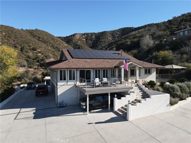 view of front facade featuring a mountain view, solar panels, and a carport