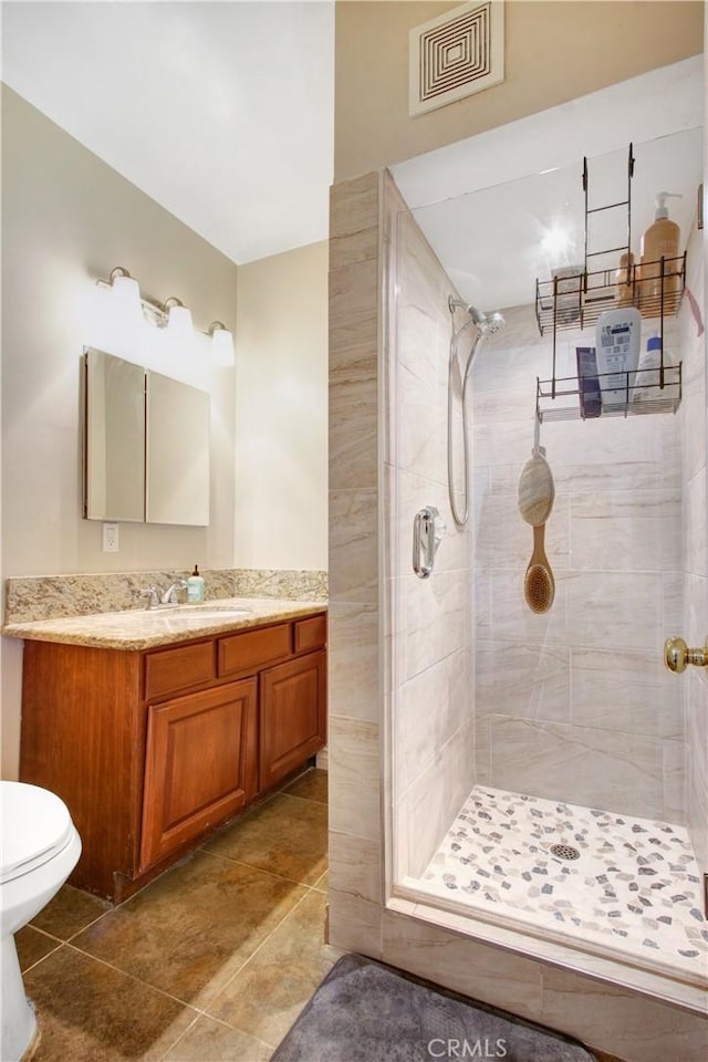 bathroom featuring toilet, vanity, and tiled shower