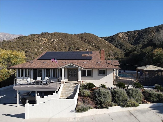 rear view of house with a mountain view and solar panels