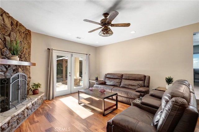 living room with ceiling fan, wood-type flooring, french doors, and a fireplace