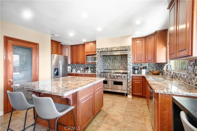 kitchen with light stone countertops, sink, a center island, and stainless steel appliances