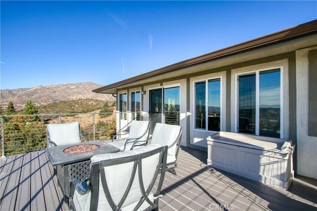 wooden deck featuring a mountain view and a fire pit