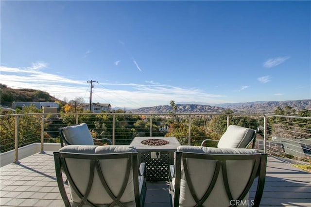 deck with an outdoor fire pit and a mountain view