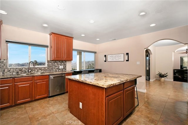 kitchen featuring dishwasher, a kitchen island, decorative backsplash, sink, and light stone counters