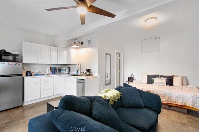 kitchen featuring ceiling fan, stainless steel appliances, white cabinetry, and sink