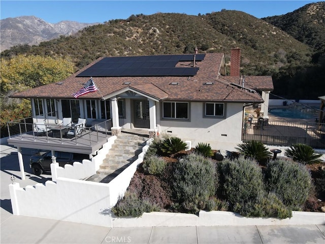 back of property featuring a mountain view, an outdoor living space, and solar panels