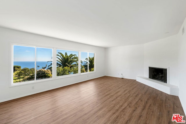 unfurnished living room with wood-type flooring, a wealth of natural light, and a water view