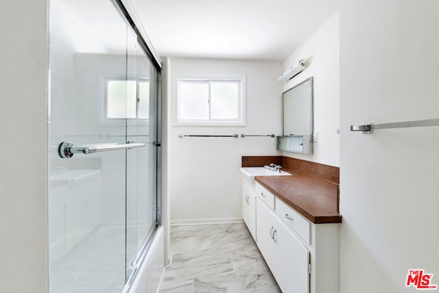 bathroom featuring bath / shower combo with glass door and vanity