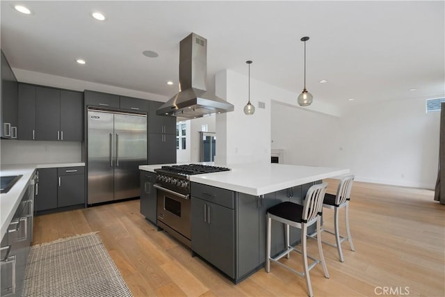 kitchen featuring island exhaust hood, gray cabinetry, high end appliances, a kitchen island, and pendant lighting