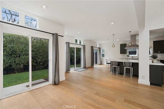 3308 Pacific Ave, Manhattan Beach, CA 90266 - kitchen featuring wall chimney range hood, light countertops, light wood finished floors, a breakfast bar, and recessed lighting