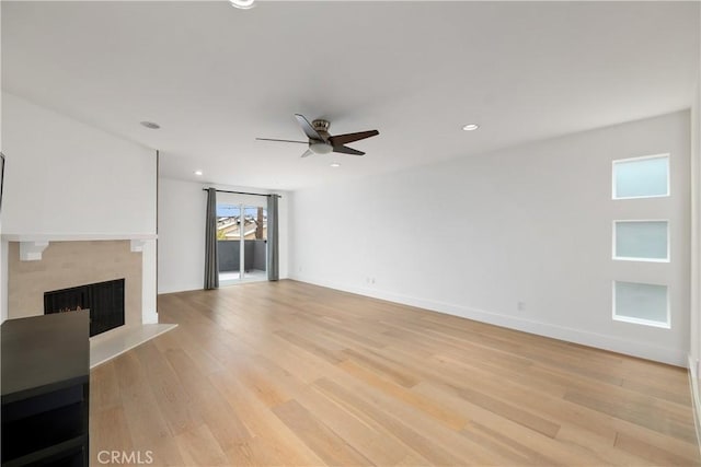 unfurnished living room featuring ceiling fan, light hardwood / wood-style flooring, and a premium fireplace