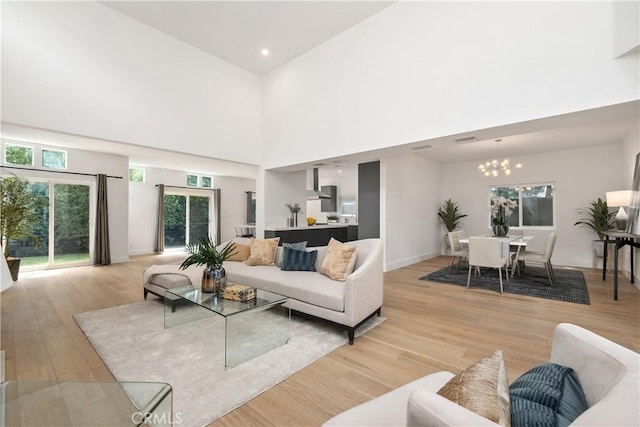 living room with light wood-type flooring, a high ceiling, and a chandelier