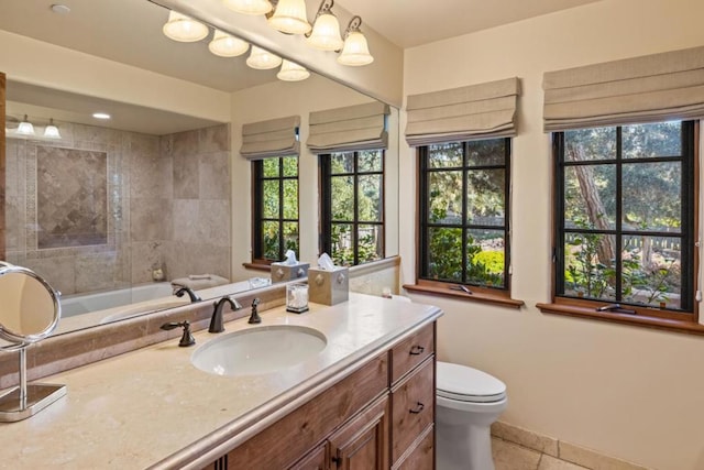 bathroom with a healthy amount of sunlight, tile patterned floors, toilet, and vanity