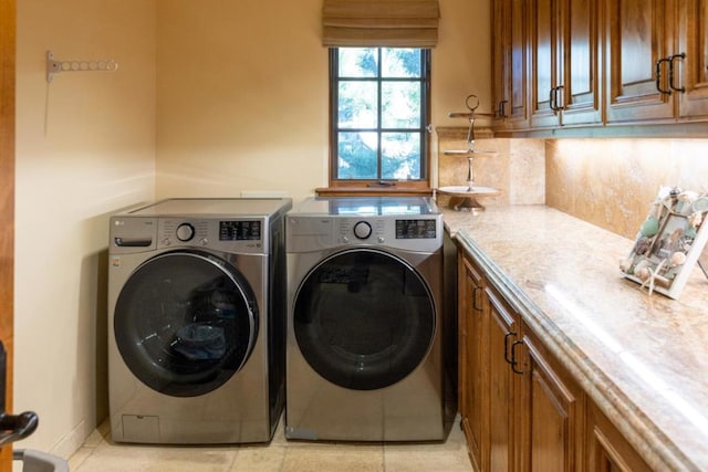 washroom with cabinets, light tile patterned floors, and washing machine and clothes dryer