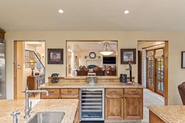 kitchen featuring high end fridge, sink, light stone counters, light tile patterned floors, and beverage cooler