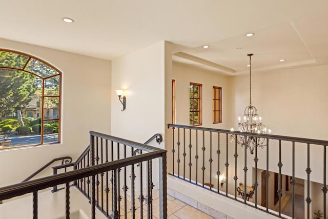 hallway featuring a chandelier, a raised ceiling, and light tile patterned floors