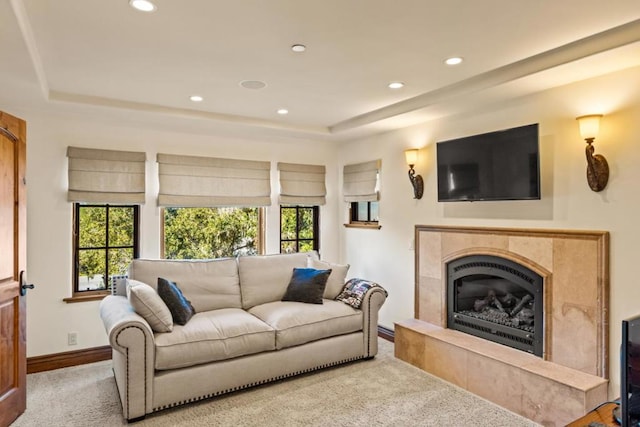 carpeted living room featuring a fireplace, a raised ceiling, and a wealth of natural light