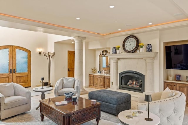 living room with crown molding, a premium fireplace, a raised ceiling, and french doors