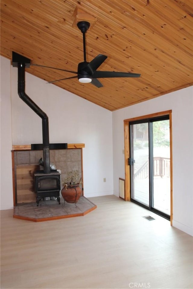 living room featuring wood ceiling, light hardwood / wood-style floors, ceiling fan, a wood stove, and vaulted ceiling