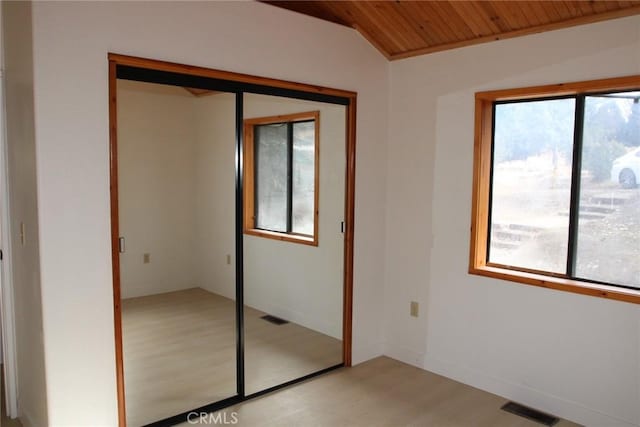 unfurnished bedroom featuring lofted ceiling, wooden ceiling, a closet, and light hardwood / wood-style floors