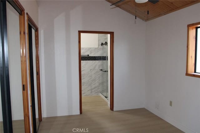 corridor with light hardwood / wood-style floors and wooden ceiling