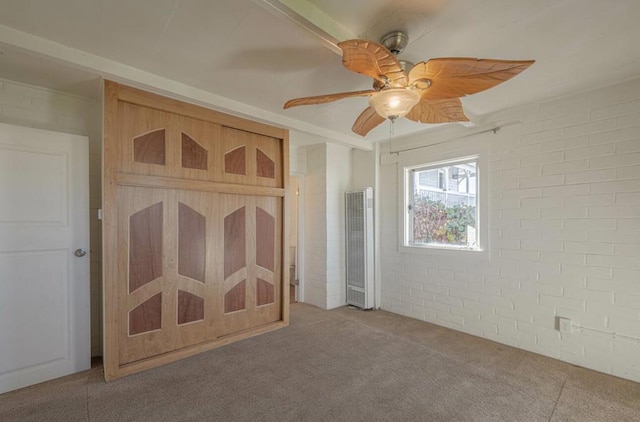 unfurnished bedroom with ceiling fan, light carpet, and brick wall