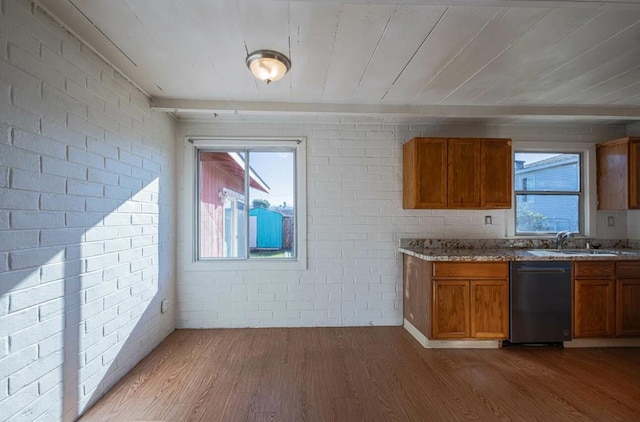 kitchen featuring hardwood / wood-style flooring, light stone countertops, brick wall, and dishwasher