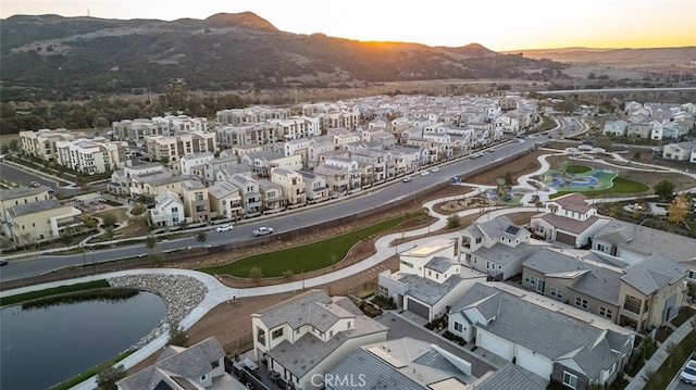 aerial view at dusk featuring a water and mountain view