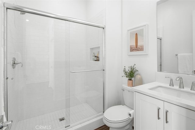 bathroom with vanity, a shower with door, and toilet